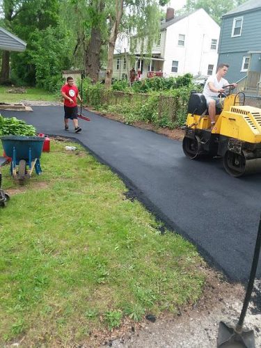 A man and woman collaborate on a driveway project, using tools and materials to enhance the outdoor space.